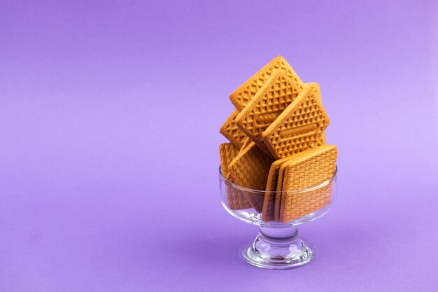 Stack of square biscuits in glass dish isolated on purple violet background