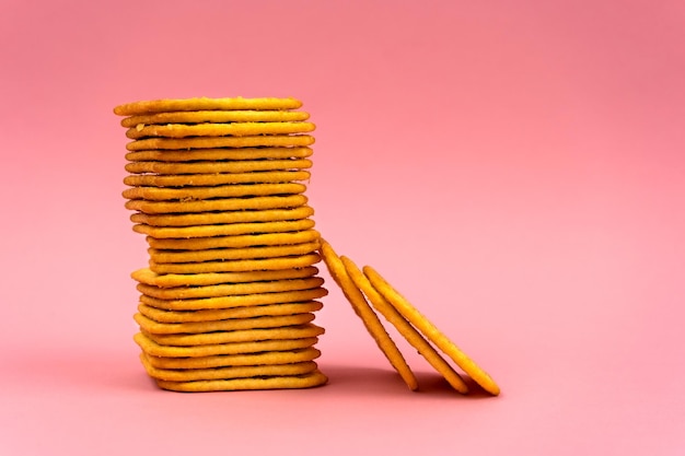 Stack of square crackers on a pink background Dry cracker cookies as a snack for lunch Copy space