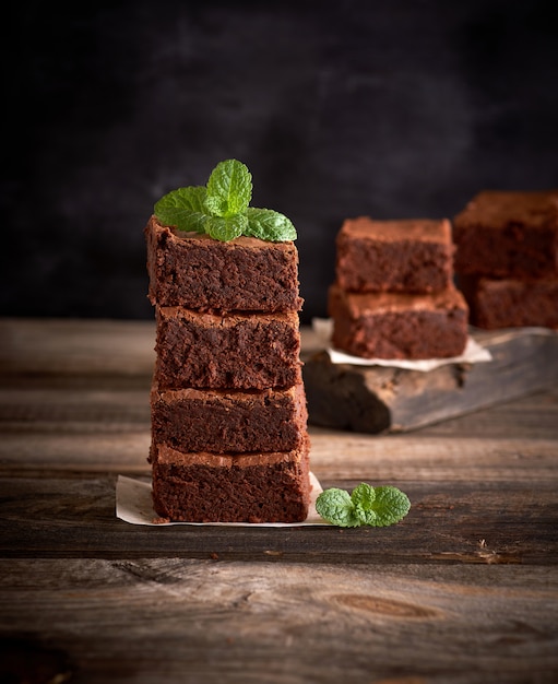 Stack of square pieces of baked brownie pie on a wooden board