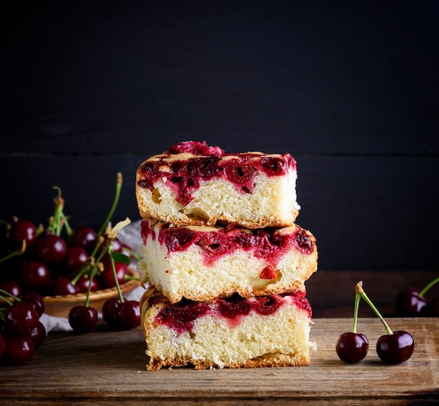 A stack of square slices of a baked pie with cherry berries 