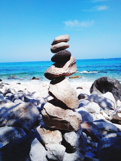 Stack of stones on beach against sky