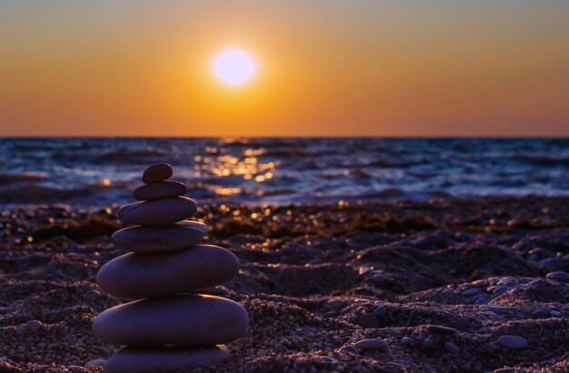 Foto una pila di pietre sulla spiaggia durante il tramonto