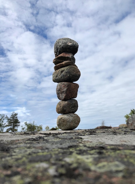 Stack of stones on field against sky