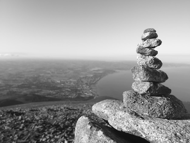 Photo stack of stones on rock by sea against sky