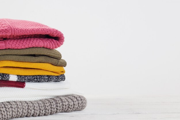 Stack of sweaters on  white wooden table