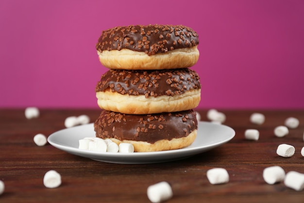 Stack of tasty glazed donuts on color background