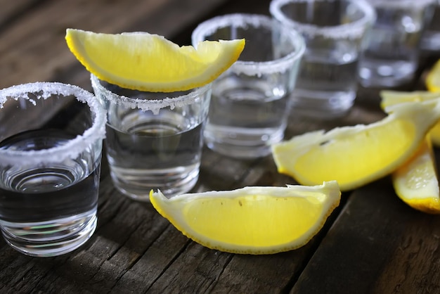 Photo stack of tequila with salt and lemon on a wooden background