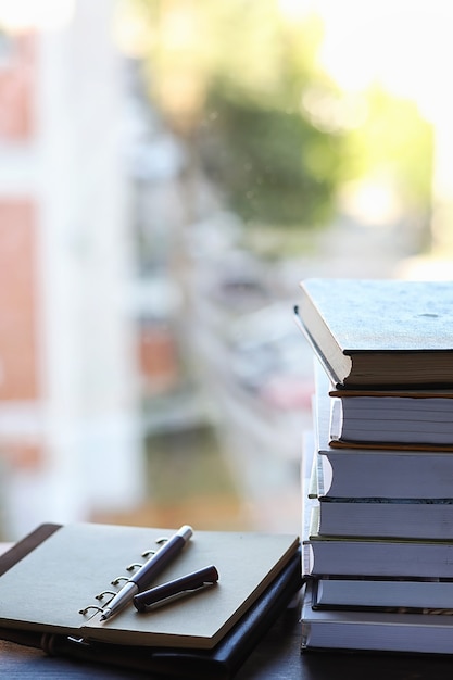 A stack of textbooks on the windowsill and writing utensils