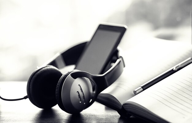 A stack of textbooks with black headphones on a table