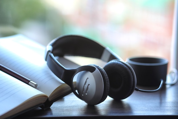 A stack of textbooks with black headphones on a table