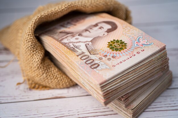 Photo stack of thai baht banknotes on wooden table, business saving finance investment concept.