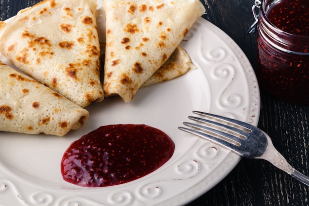 Stack of thin pancakes (bliny) or crepes with raspberry and sour cream. Traditional for the Russian pancake week