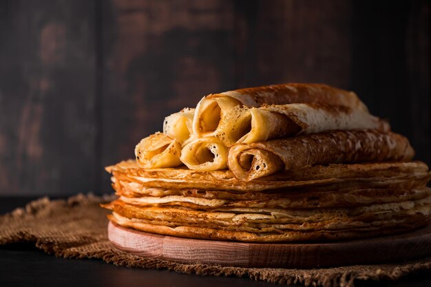 Foto una pila di pancake sottili su uno sfondo di legno scuro un piatto tradizionale di crepe