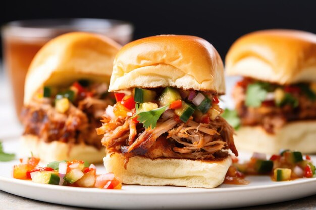 Stack of three bbq pork sliders with spicy salsa on the side