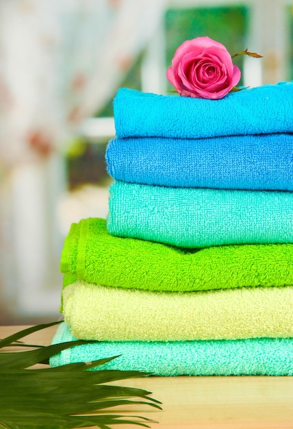 Stack of towels with fragrant flower on window background