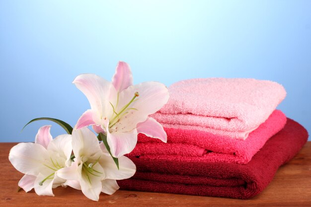 Stack of towels with pink lily on blue table