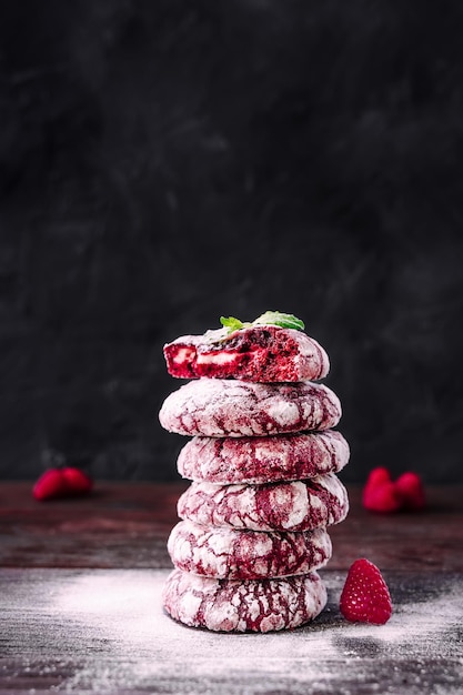 Stack or tower of cookies Red velvet cookies Chefs hands with small sieve for baking sprinkling powdered sugar Baker decorating and sprinkling stack of cookies Dark background colourful food