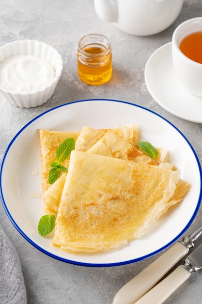 Stack of traditional thin pancakes or crepes with honey and sour cream Food for Maslenitsa