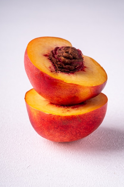 Stack of two slice of peach nectarine fruit with seed on white wall