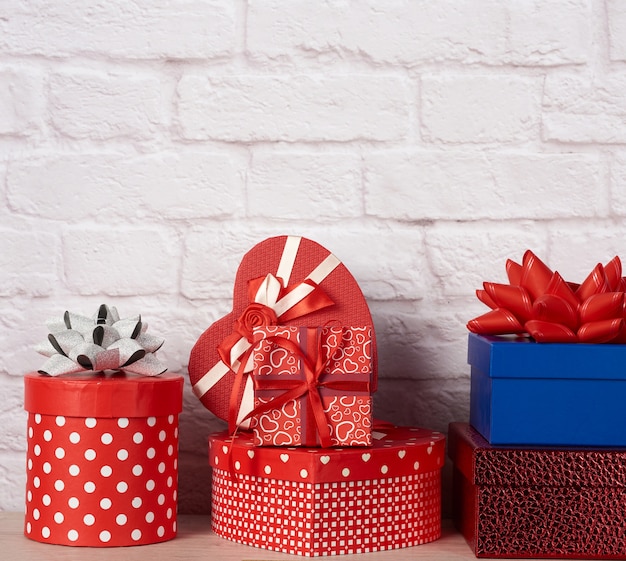 Stack of various boxes with gifts on white brick wall