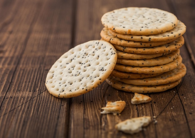 Stack of various organic crispy wheat flatbread crackers with sesame and salt on wood background