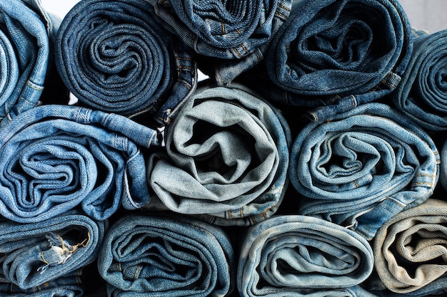 Pila di jeans blu di varie tonalità jeans impilati isolati su sfondo bianco striscione texture jeans blu denim con spazio copia per sfondo design testo tela denim moda texture