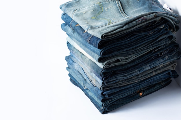 Stack of various shades blue jeans Jeans stacked isolated on white background Blue denim jeans texture banner with copy space for text design background Canvas denim fashion texture