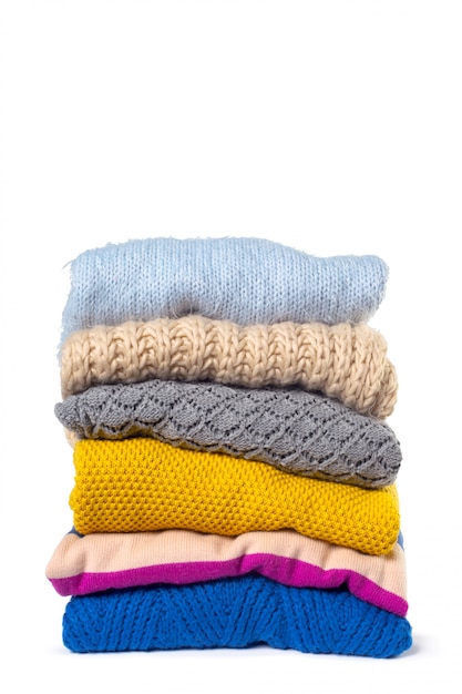 Stack of various sweaters isolated on white 