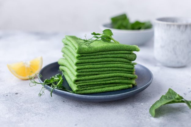 Stack of vegan spinach crepes garnished with microgreens