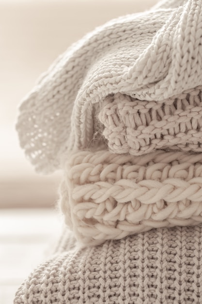 A stack of warm knitted items on blurred white background.