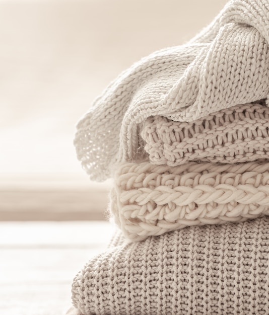 A stack of warm knitted items on blurred white background.