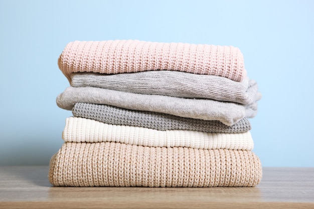 A stack of warm sweaters on the table on a colored background