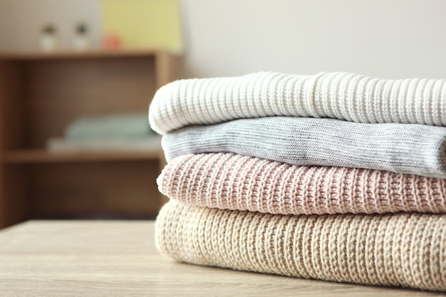 A stack of warm sweaters on the table on a colored background