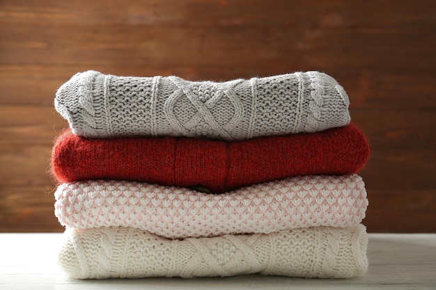 Stack of warm winter clothes on wooden background