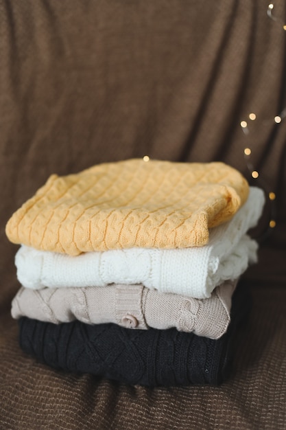 A stack of warm woolen knitted sweaters on a dark background