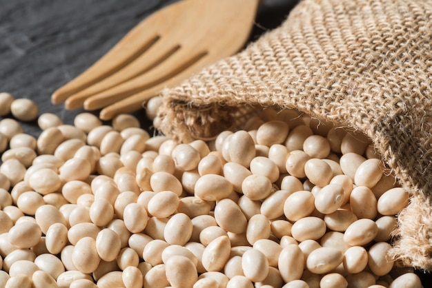 Foto pila di fagioli bianchi con sacchetto di tela sul tavolo