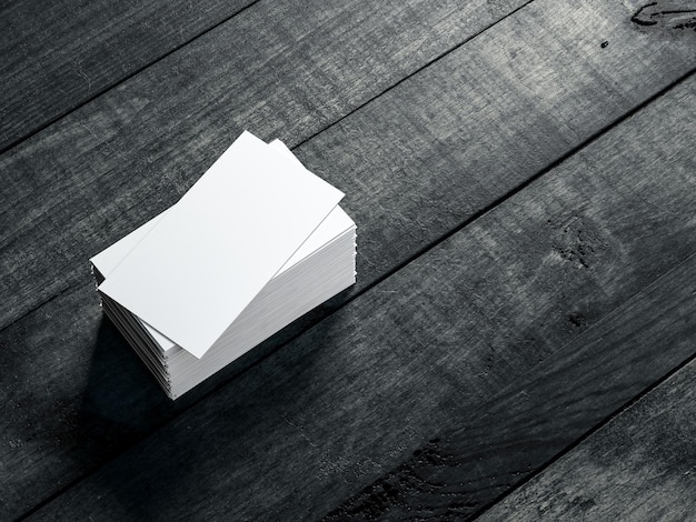 Photo stack of white business cards mockup on black wooden table, 3d rendering