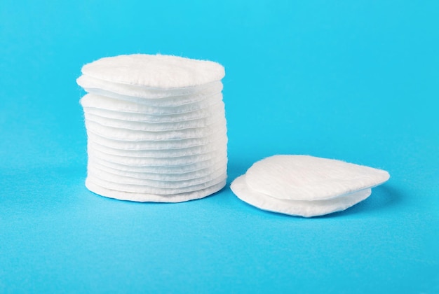 A stack of white cotton pads closeup on a blue background Skin cleaning