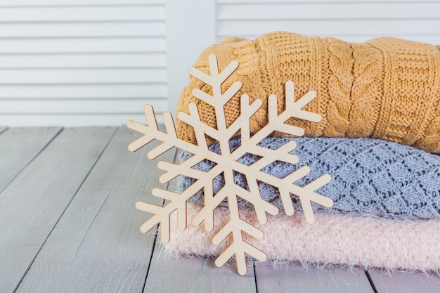 Stack of white cozy knitted sweaters on a wooden table