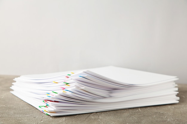 Stack of white paper with clips on grey background