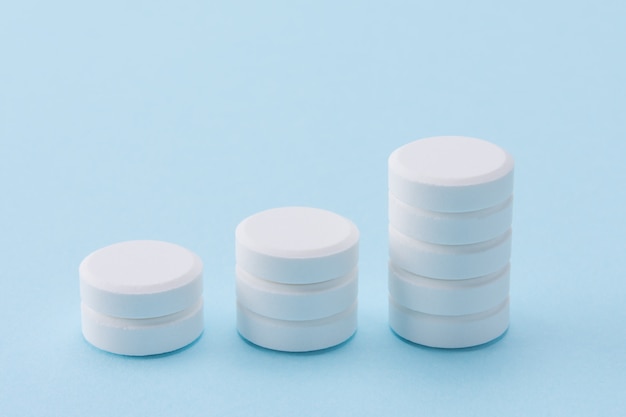 stack of white pills as bar graph on blue 