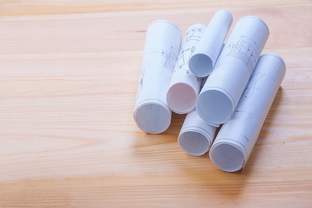 Stack of white rolled up blueprints on wooden board