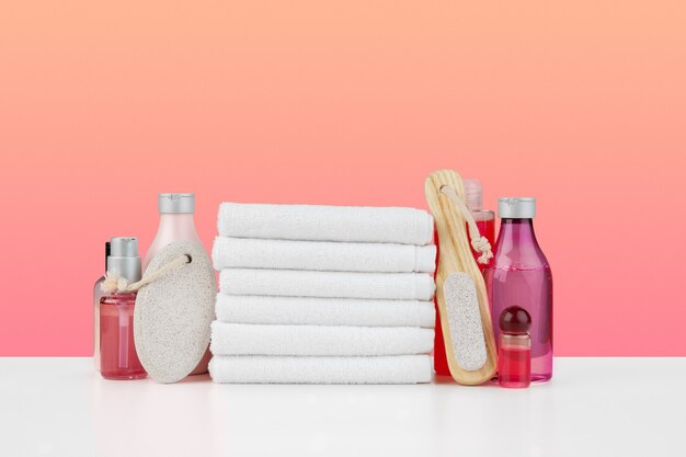 Stack of white towels and bottles of skincare on white table