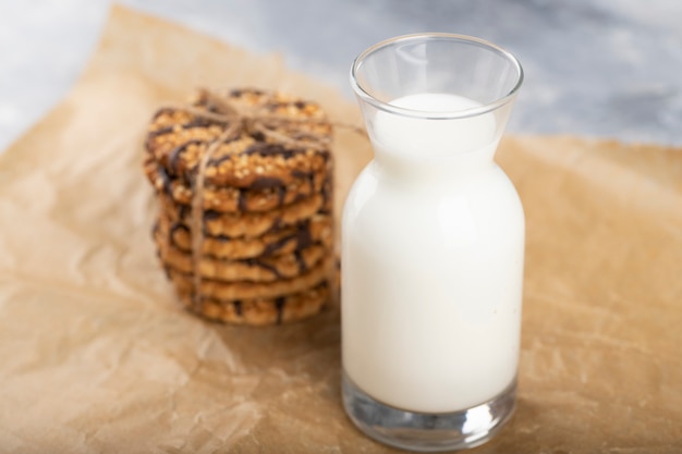 Stack of wholegrain biscuits and glass of milk on baking sheet.