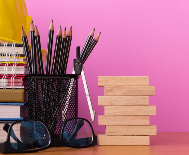 Stack wooden blocks with pencils glasses and other on wooden table isolated pick background