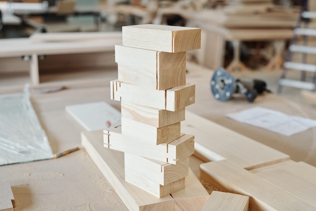 Stack of wooden brick workpieces ready to be used in production of furniture standing on workbench of modern factory worker