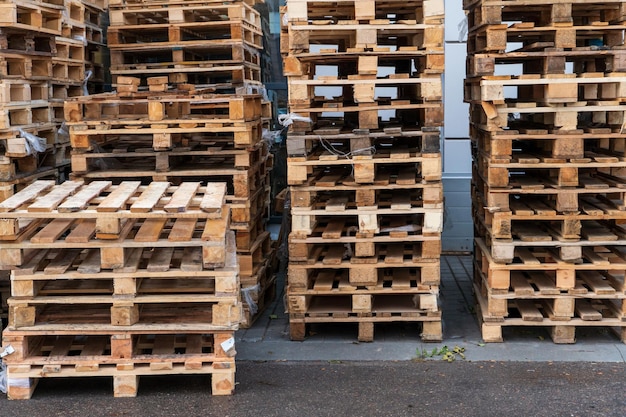 A stack of wooden pallets in an internal warehouse An outdoor pallet storage area under the roof next to the store Piles of Eurotype cargo pallets at a waste recycling facility