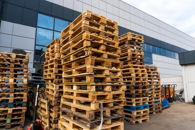 A stack of wooden pallets in an internal warehouse An outdoor pallet storage area under the roof next to the store Piles of Eurotype cargo pallets at a waste recycling facility