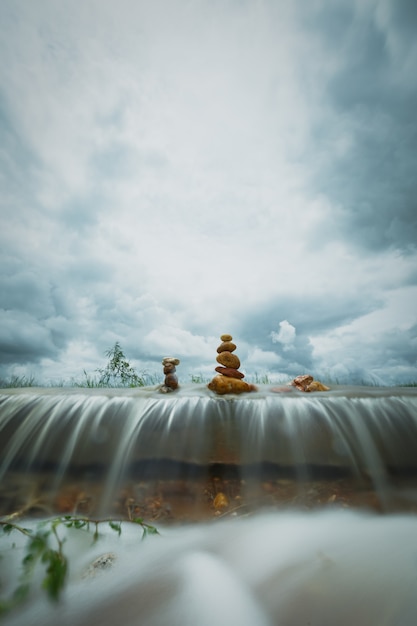 Стек дзен-камней над водопадом на фоне шторма облаков