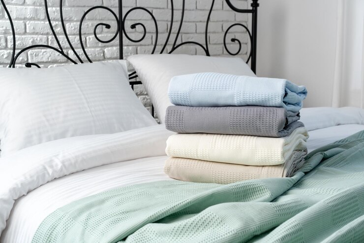 Photo stacked blankets on a white bed with black wrought iron headboard